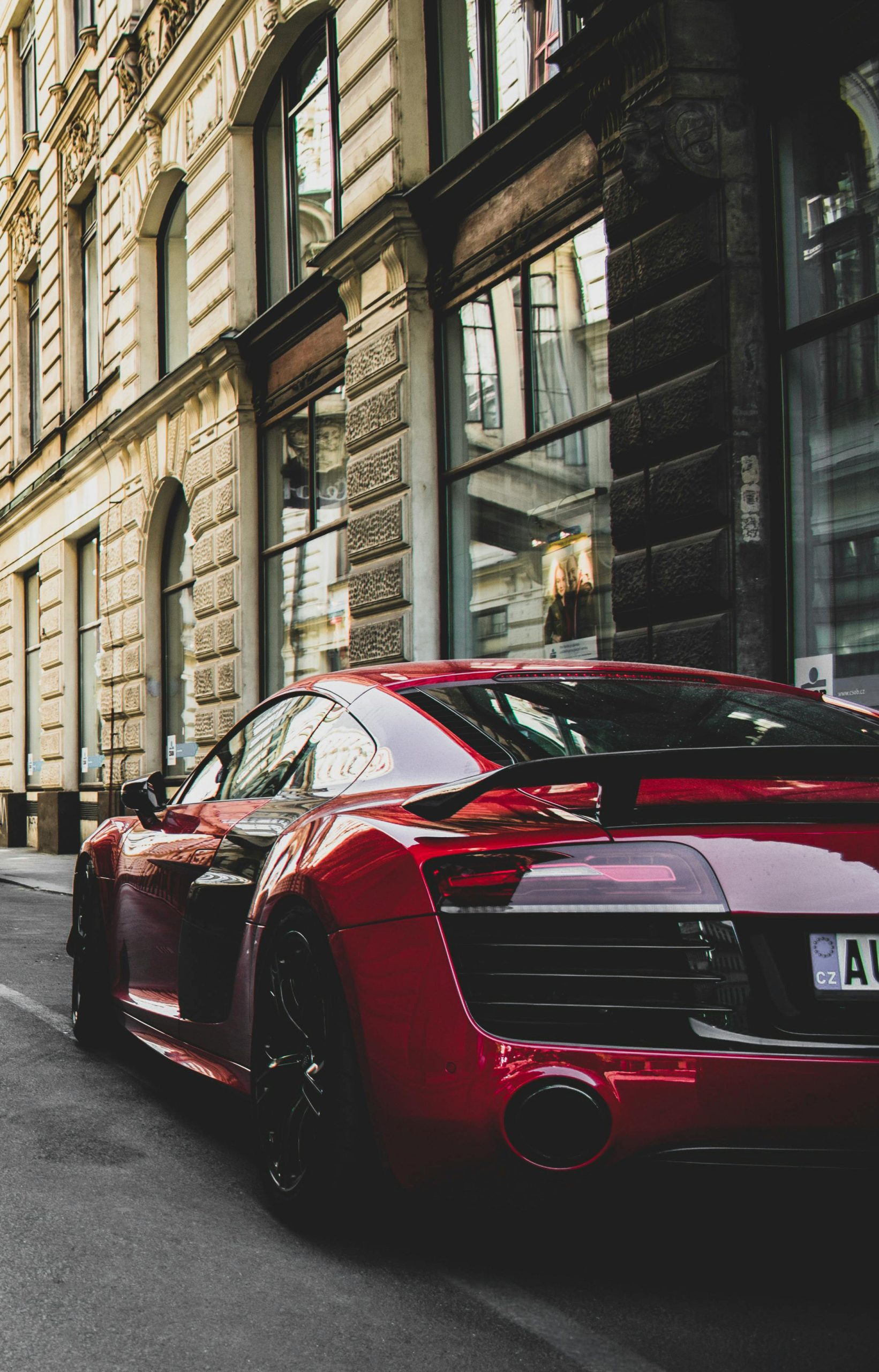 Home Sleek red sports car parked on a charming historic street in Prague, highlighting urban elegance and powerful design.