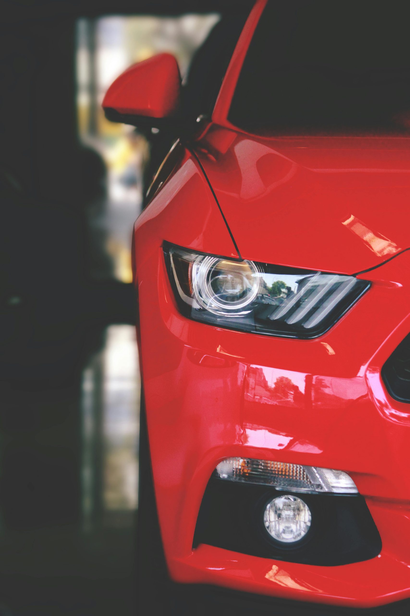 Home Detailed view of a sleek red sportscar showcasing elegant design and modern headlights.